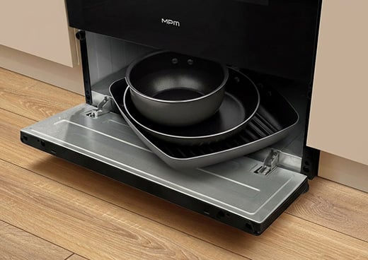Zbliżenie na dolny schowek kuchni gazowo-elektrycznej MPM-56-KGM-12B, z którego wystają garnki.