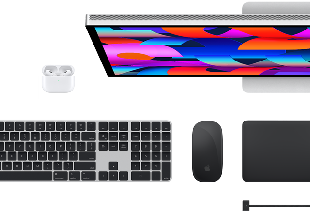 Widok z góry na wybrane akcesoria do Maca: Studio Display, Magic Keyboard, Magic Mouse, Magic Trackpad, AirPods i przewód ładujący MagSafe