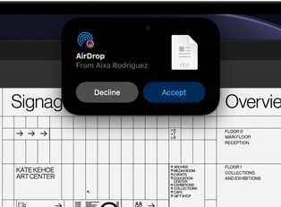 Wyświetlacz pokazuje Dynamic Island z prośbą AirDrop w małym oknie nad otwartym plikiem Adobe Acrobat