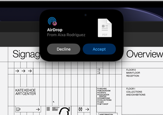 Wyświetlacz pokazuje Dynamic Island z prośbą AirDrop w małym oknie nad otwartym plikiem Adobe Acrobat