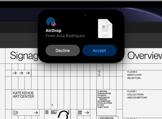 Wyświetlacz pokazuje Dynamic Island z prośbą AirDrop w małym oknie nad otwartym plikiem Adobe Acrobat