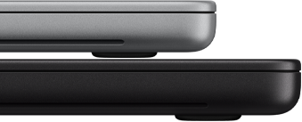 14‑calowy MacBook Pro z wyświetlaczem PROLED XDR, kolor srebrny, ułożony na modelu 16 cali w kolorze gwiezdnej czerni w celu zobrazowania różnicy w rozmiarze