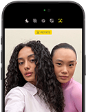 iPhone 18 Pro, kolor czarny, przód obudowy, na ekranie widoczne dwie osoby pozujące do zdjęcia, prezentacja aparatu przedniego Center Stage