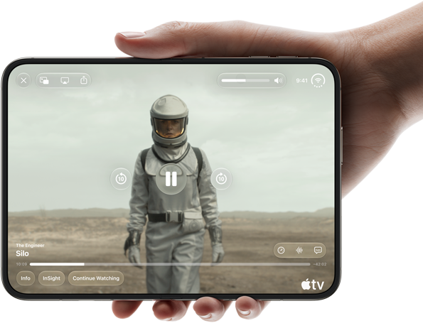 Całkowicie rozłożony iPhone Duo trzymany w jednej dłoni w pozycji poziomej, na wyświetlaczu wewnętrznym widać serial „Silos” w apce Apple TV