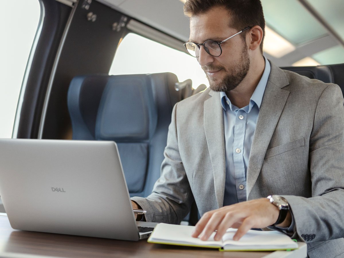 Dell 16 Pro mężczyzna w pociągu przeglądający wiadomości