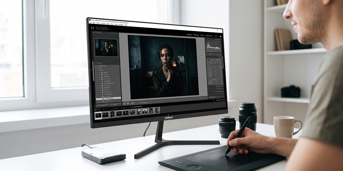Mężczyzna retuszuje portret kobiety w programie graficznym na monitorze Dahua przy użyciu tabletu piórkowego