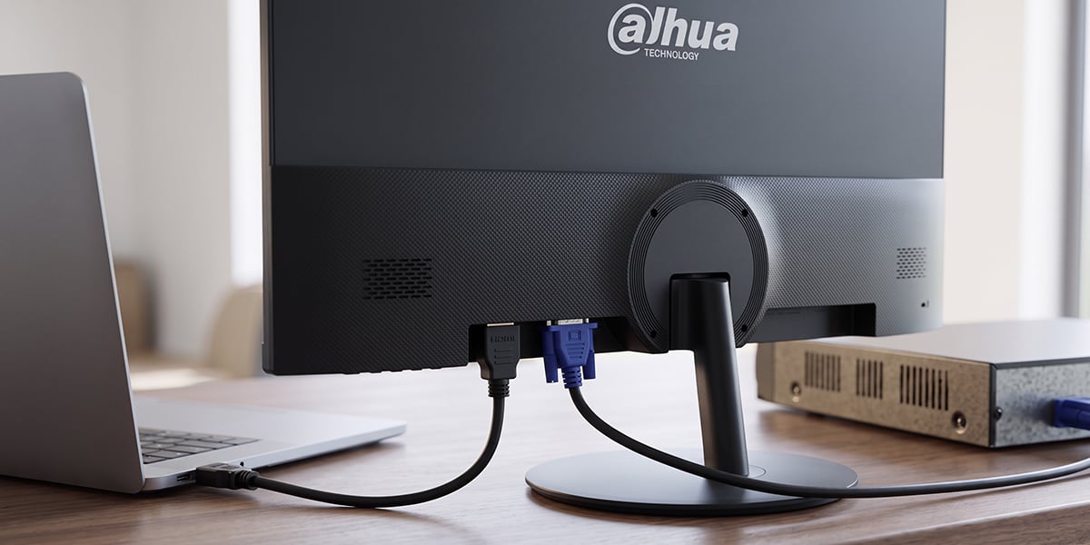 Zbliżenie na tył monitora Dahua z podłączonym przewodem HDMI do laptopa oraz niebieskim wtykiem VGA