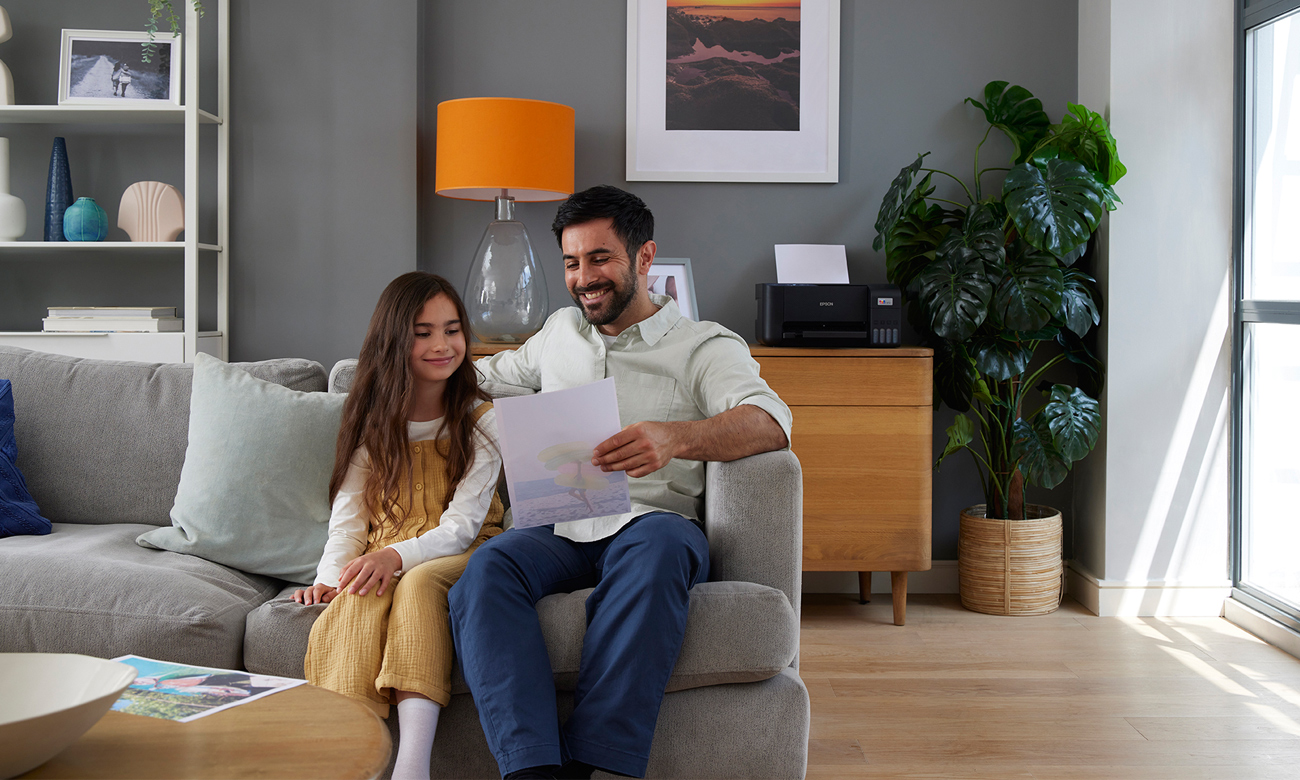 Córka z tatą oglądają wydruk z urządzenia Epson EcoTank L3211