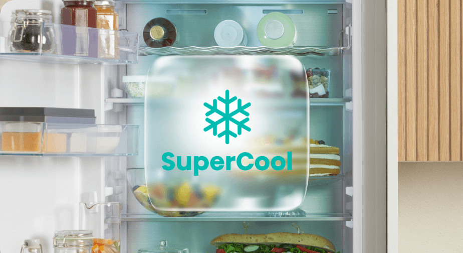 Zielony symbol SuperCool ze śnieżynką na zamglonym kwadracie, na tle wnętrza otwartej lodówki z produktami.