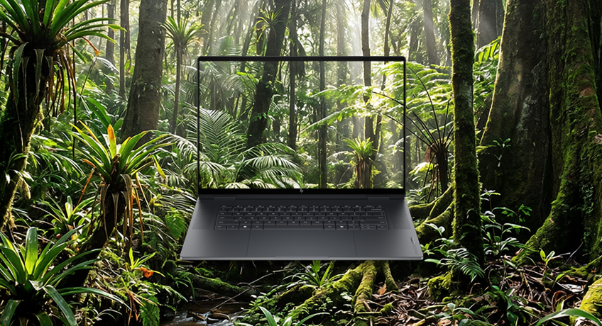 Czarny laptop HP OmniBook Ultra wyświetla tropikalny las na ekranie w otoczeniu roślinności.