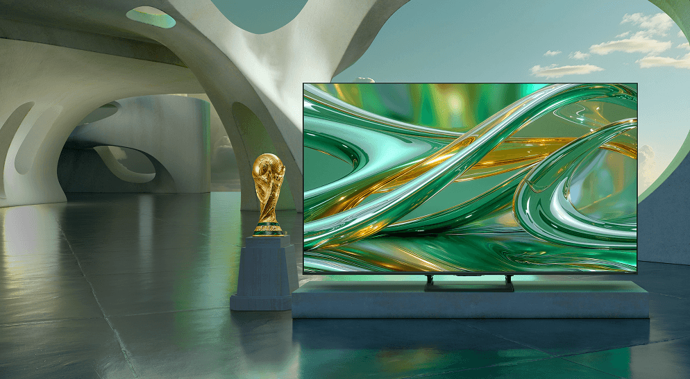 Telewizor z zieloną grafiką obok Pucharu Świata FIFA na postumencie, umieszczony w futurystycznym wnętrzu z betonowymi łukami