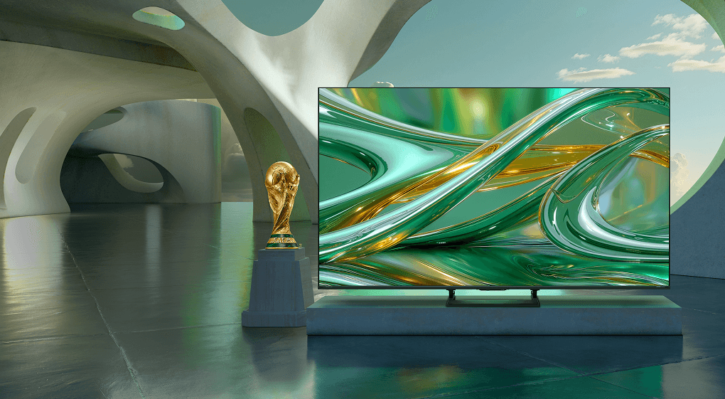 Telewizor z zieloną grafiką obok Pucharu Świata FIFA na postumencie, umieszczony w futurystycznym wnętrzu z betonowymi łukami