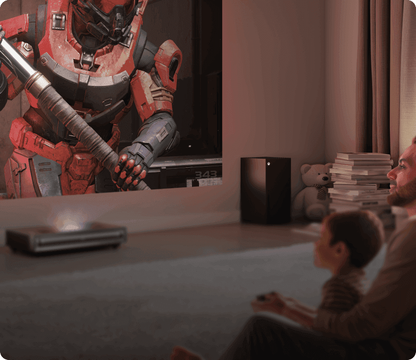 Mężczyzna i dziecko na dywanie grają w Halo Infinite. Projektor Hisense wyświetla na ścianie postacie w pancerzach.
