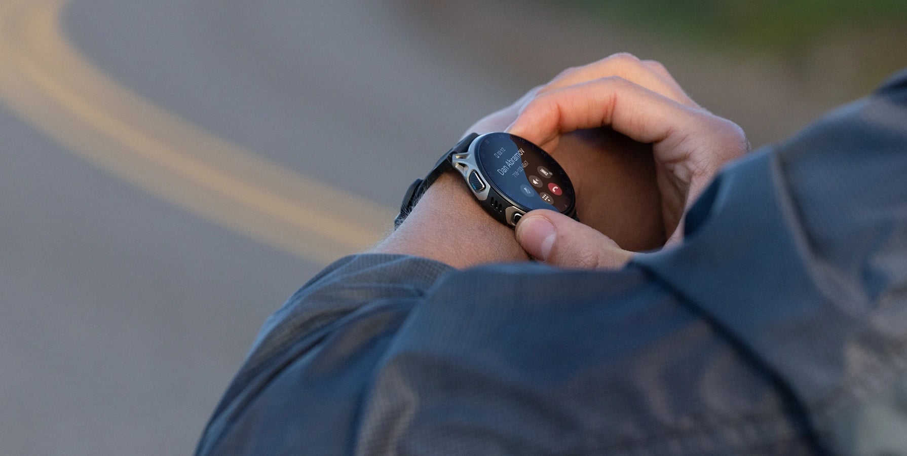 Osoba obsługuje smartwatch na nadgarstku, na ekranie widoczne opcje połączenia telefonicznego
