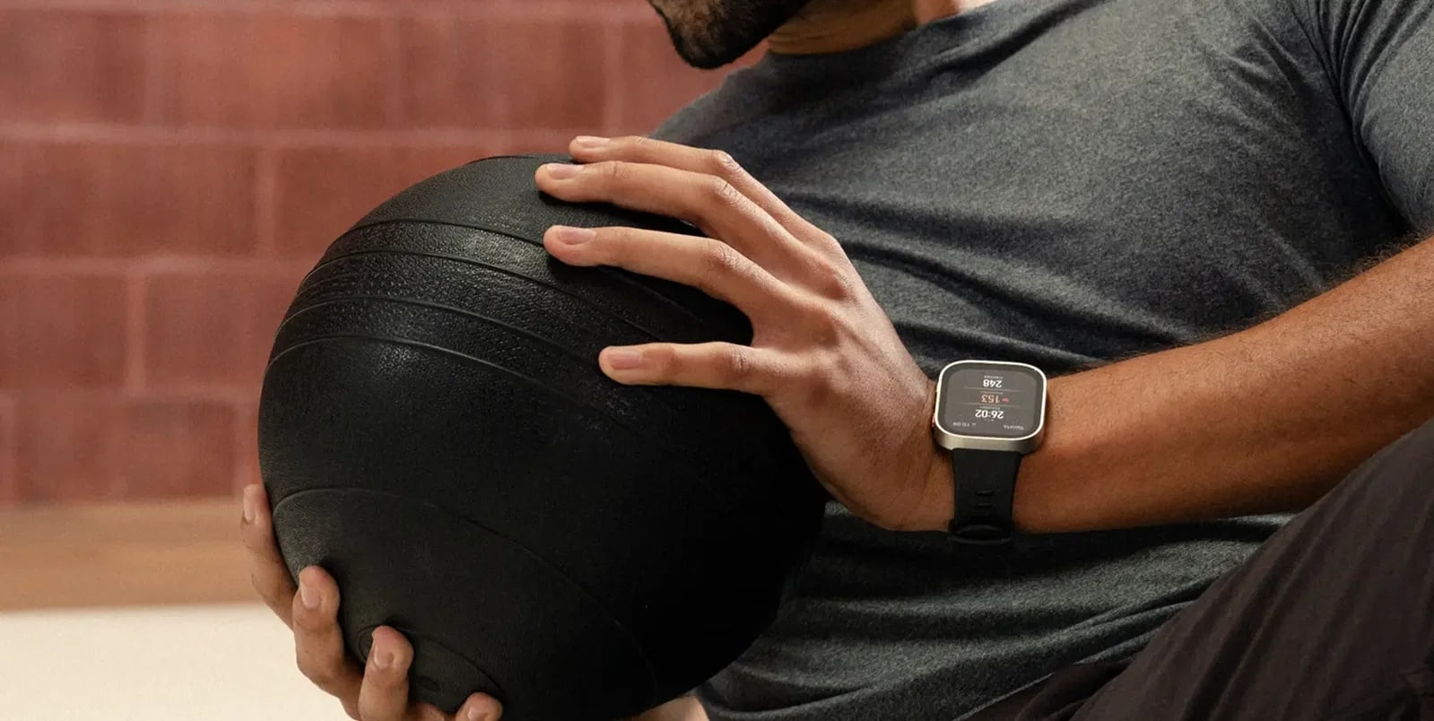 Smartwatch Bip-Max na nadgarstku mężczyzny ćwiczącego z ciężką piłką lekarską.