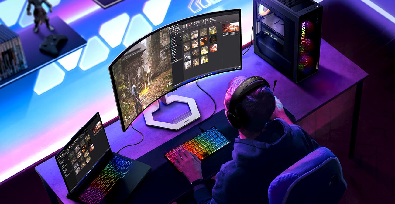Na biurku monitor Lenovo Legion Pro 34WD-10, otwarty laptop i stacja robocza, widoczna podświetlona klawiatura