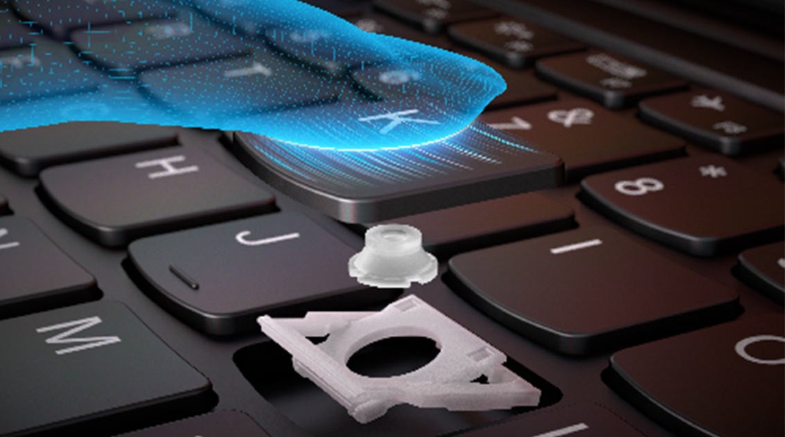 Widoczny fragment klawiatury laptopa Yoga Slim 7i w dużym zbliżeniu, pokazany mechanizm jednego z klawiszy nad którym unosi się wirtualny palec w kolorze niebieskim