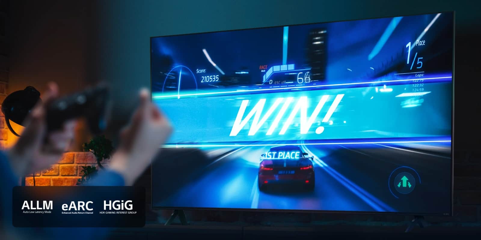 Samochody wyścigowe na linii mety z napisem „WIN!”. Gracz trzyma joystick. Logo ALLM, eARC i HGiG znajduje się w lewym dolnym rogu.