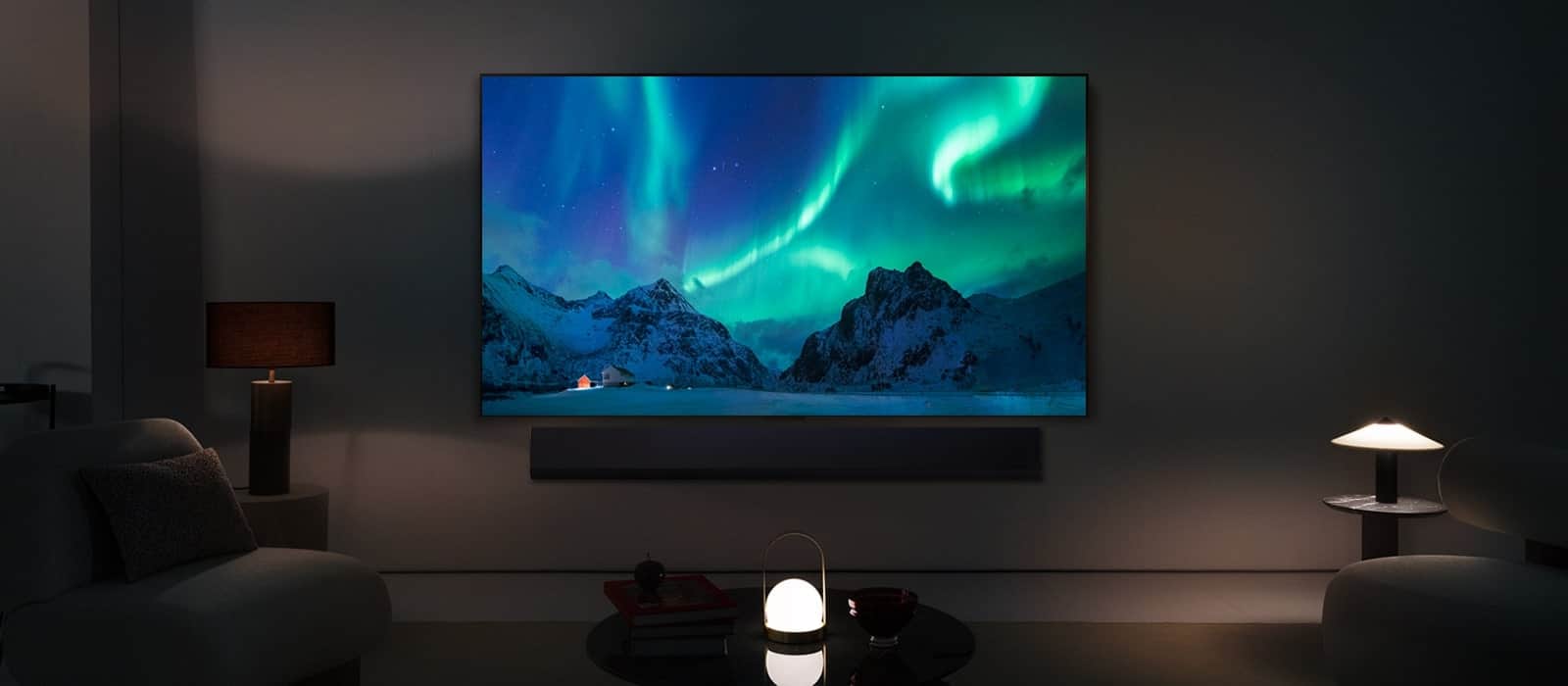 LG OLED TV i soundbar LG w nowoczesnej przestrzeni nocnej. Obraz zorzy polarnej wyświetlany jest z idealnym poziomem jasności.