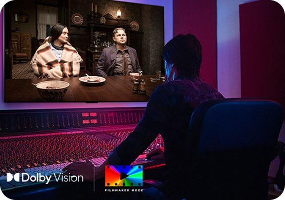 Mężczyzna siedzi w studiu montażowym, przed nim mnóstwo przycisków, a na wprost niego ekran, na którym widać dwoje ludzi