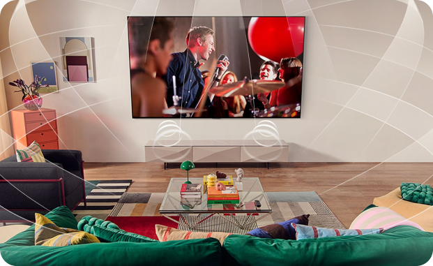 Zawieszony na ścianie w pokoju, duży telewizor z płaskim ekranem, na którym widnieje koncert zespołu muzycznego