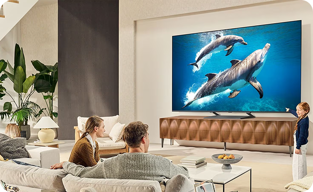 Rodzina w jasnym przestronnym salonie ogląda film przyrodniczy na dużym, płaskim telewizorze ściennym