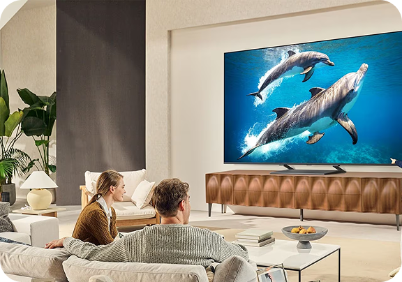 Rodzina w jasnym przestronnym salonie ogląda film przyrodniczy na dużym, płaskim telewizorze ściennym