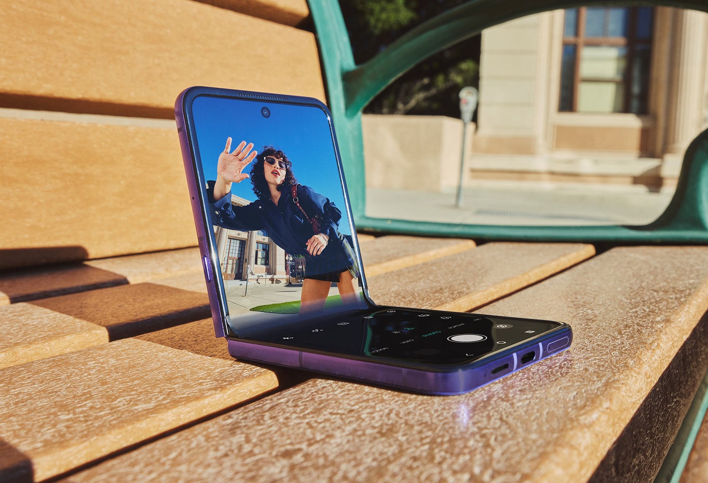 Smartfon razr 70 ultra ustawiony w trybie Flex View na drewnianej ławce, ze zdjęciem kobiety.