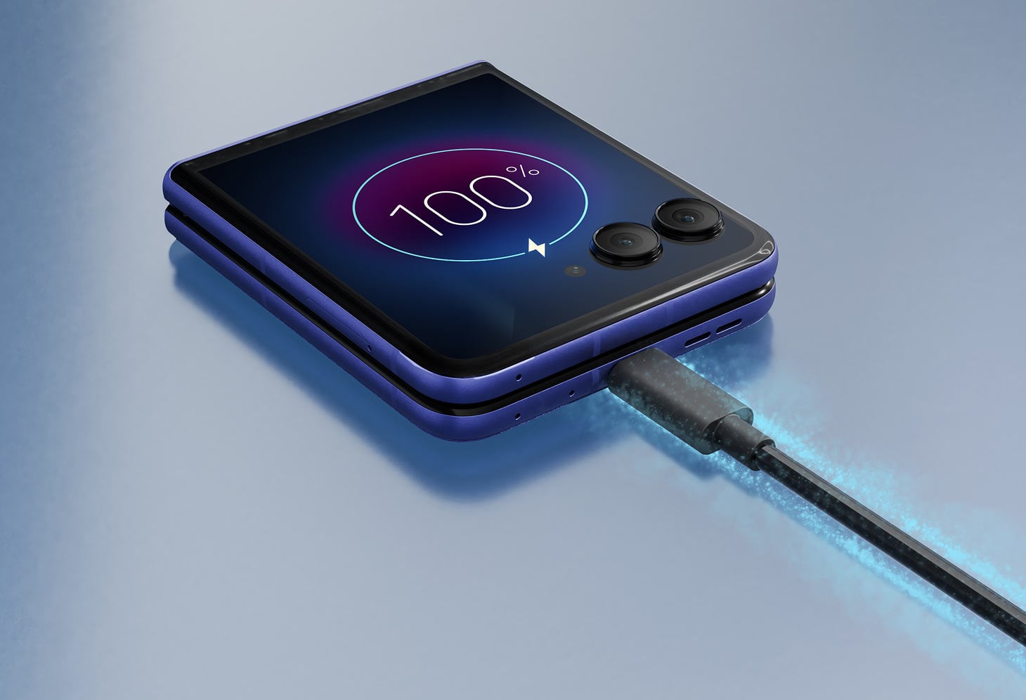 Złożony smartfon razr 70 ultra podpięty do kabla, wyświetlający 100% naładowania.