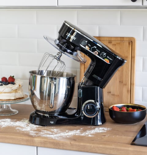 Robot planetarny MRK-19 na kuchennym blacie, wokół rozsypana mąka, beza i truskawki.