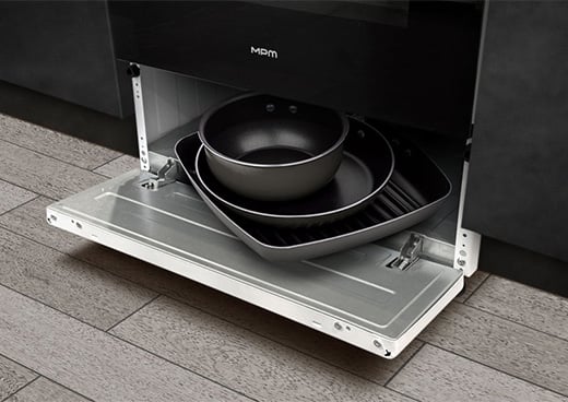 Wysunięta szuflada pod piekarnikiem kuchni gazowo-elektrycznej MPM-66-KGM-10. W środku patelnie.