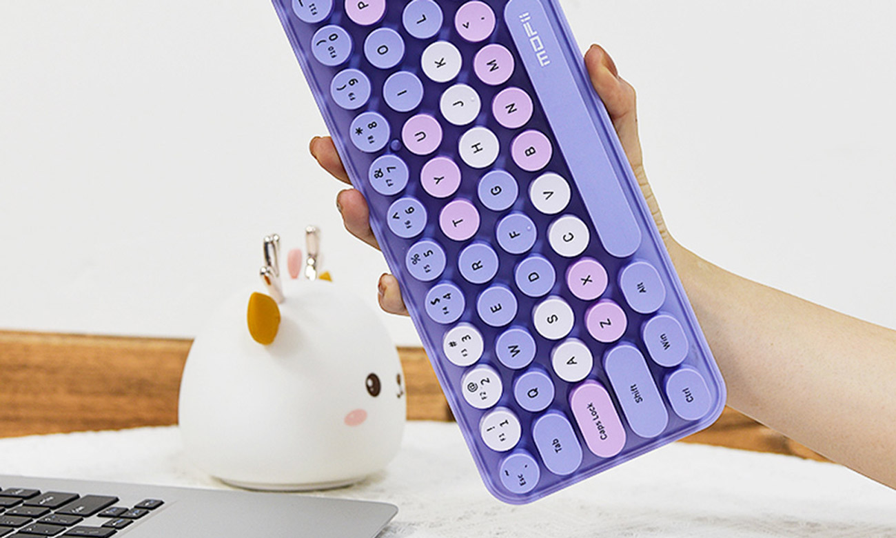 Kobieta trzyma klawiaturę Mofii Bean 2.4G koło laptopa