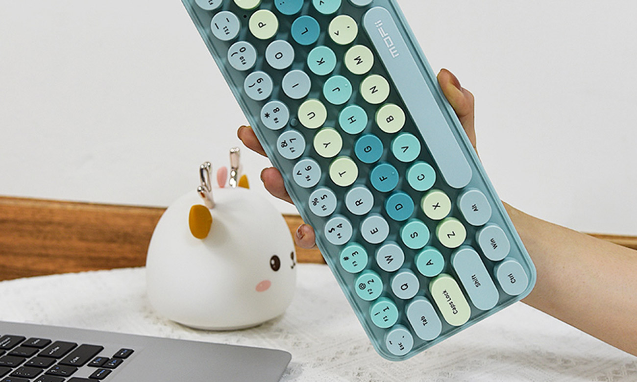 Kobieta trzyma klawiaturę Mofii Bean 2.4G koło laptopa