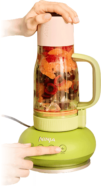 Zielony blender BlendBoss z kielichem pełnym owoców; dłoń naciska przycisk 'pulse' na podstawie