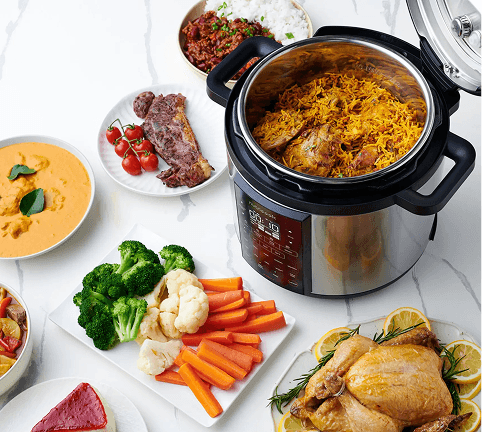 Otwarty multicooker z potrawą z ryżu w środku, otoczony miskami i talerzami z kurczakiem, warzywami oraz gulaszem