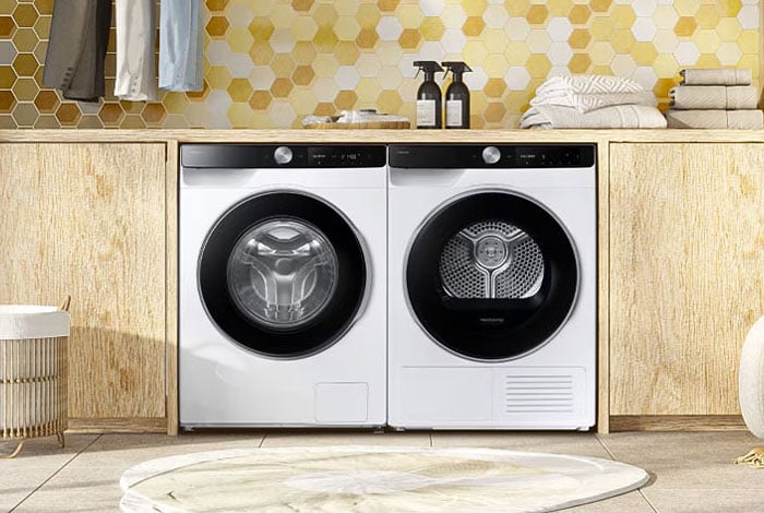 Suszarka AI 9kg DV90DG6845LKU4 Biała suszarka AI z pralką Samsung ustawione obok siebie w nowoczesnej zabudowie meblowej w pralni.