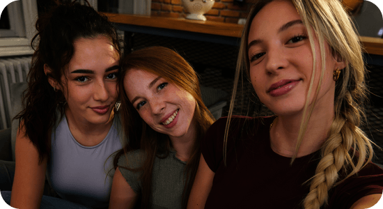 Trzy dziewczyny na kanapie robią selfie w słabym świetle; Nightography Galaxy A37 5G daje jasne, żywe detale.