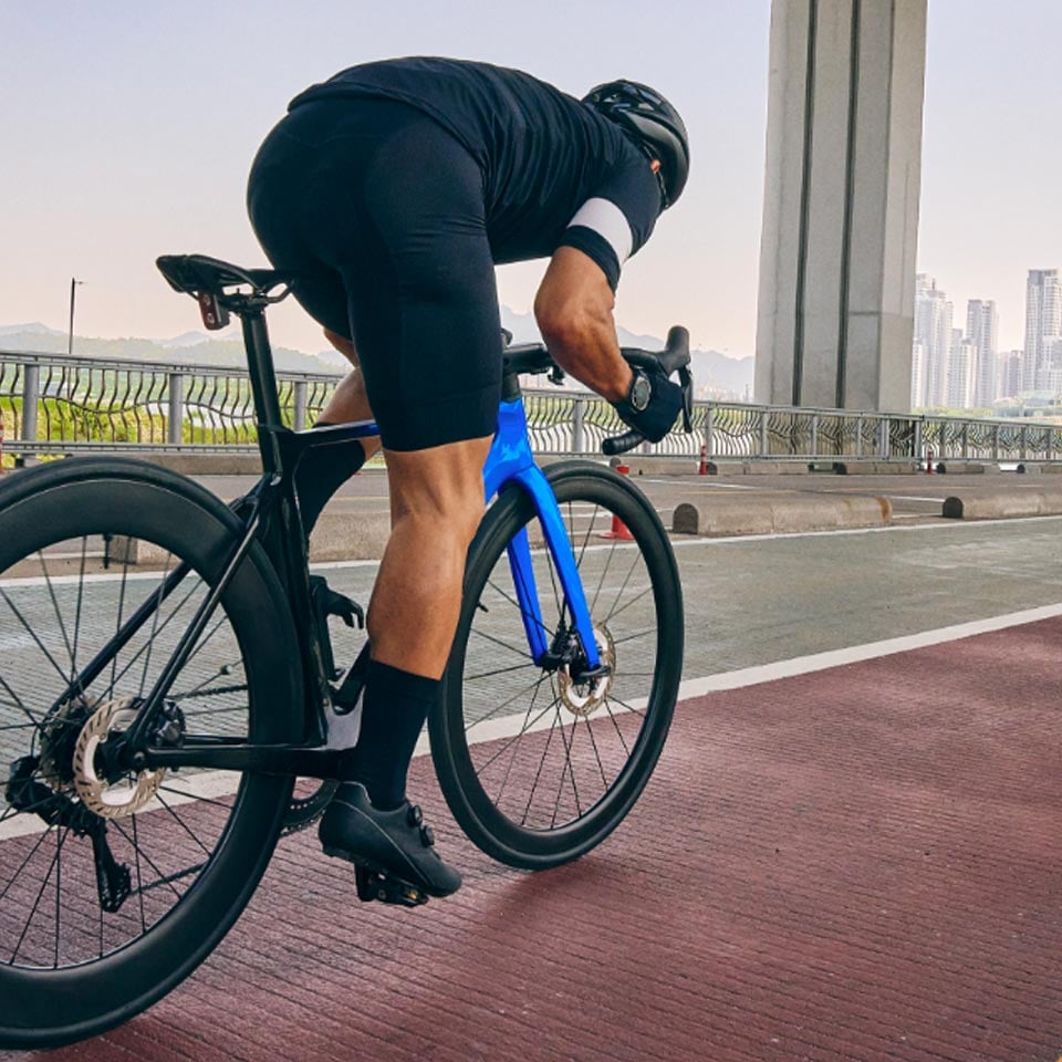Mężczyzna w stroju kolarskim jedzie na rowerze szosowym po ścieżce rowerowej. Mężczyzna w stroju kolarskim jedzie na rowerze szosowym po ścieżce rowerowej.