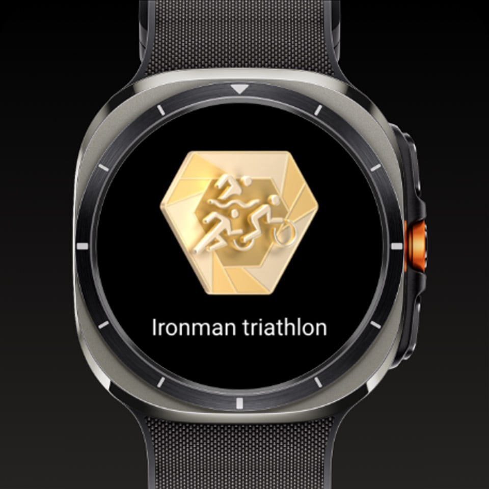 Galaxy Watch Ultra wyświetlający odznakę kamienia milowego i tekst „Ironman triathlon Galaxy Watch Ultra wyświetlający odznakę kamienia milowego i tekst „Ironman triathlon