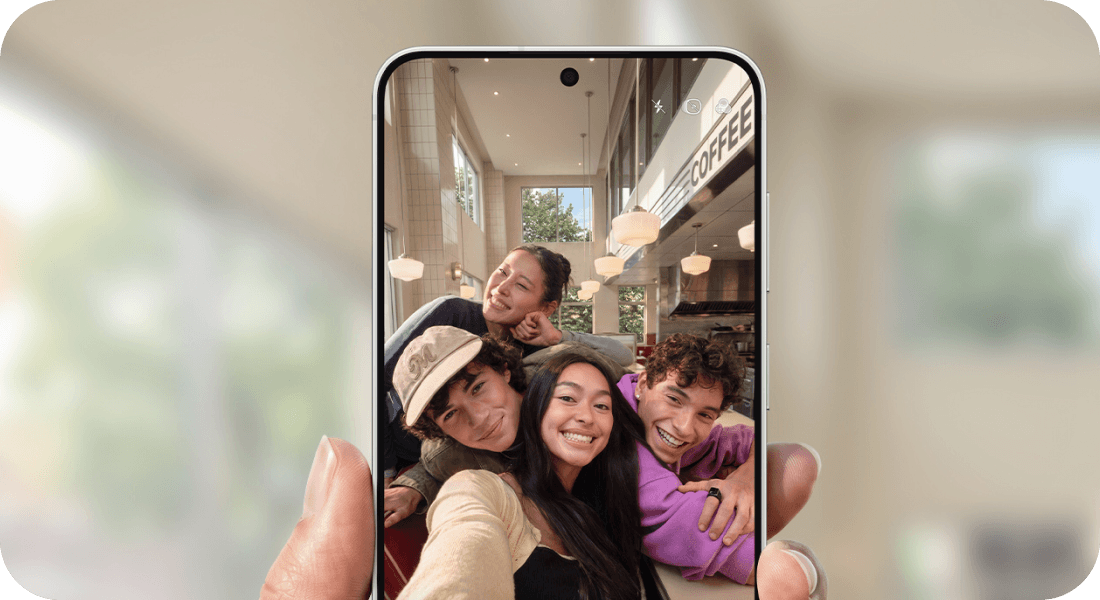 Czworo znajomych robi grupowe selfie przednim aparatem smartfona Galaxy.