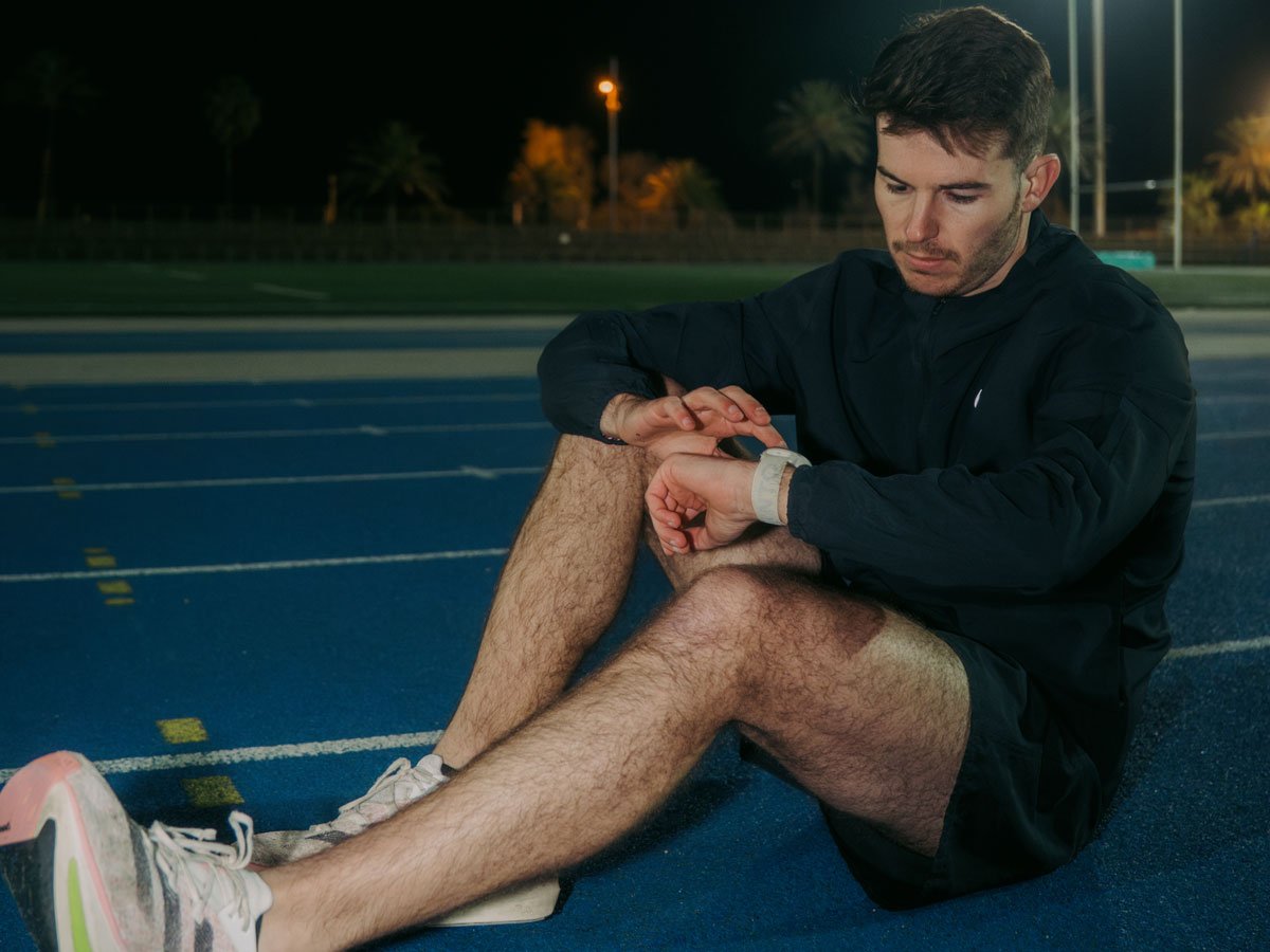 Suunto Run mężczyzna siedzący na bieżni sprawdzający zegarek