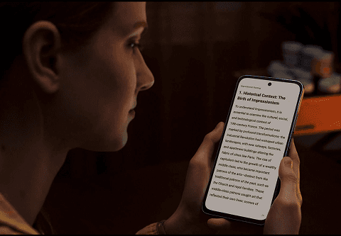 Kobieta trzyma w dłoniach smartfon z wyświetlanym anglojęzycznym tekstem o historii impresjonizmu