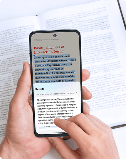 Dłoń trzyma smartfon nad książką, a palec drugiej dłoni wybiera opcję Rewrite w oknie edycji tekstu