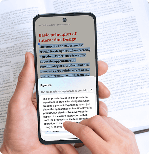 Dłoń trzyma smartfon nad książką, a palec drugiej dłoni wybiera opcję Rewrite w oknie edycji tekstu