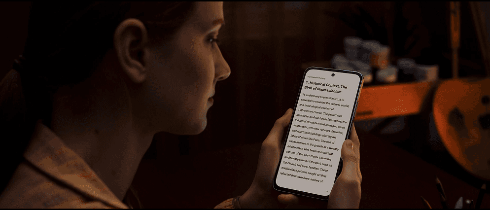Kobieta trzyma w dłoniach smartfon z wyświetlanym anglojęzycznym tekstem o historii impresjonizmu