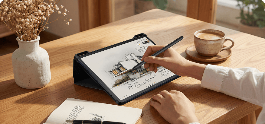 Dłoń rysująca rysikiem szkic architektoniczny na ekranie tabletu w czarnym etui na drewnianym biurku