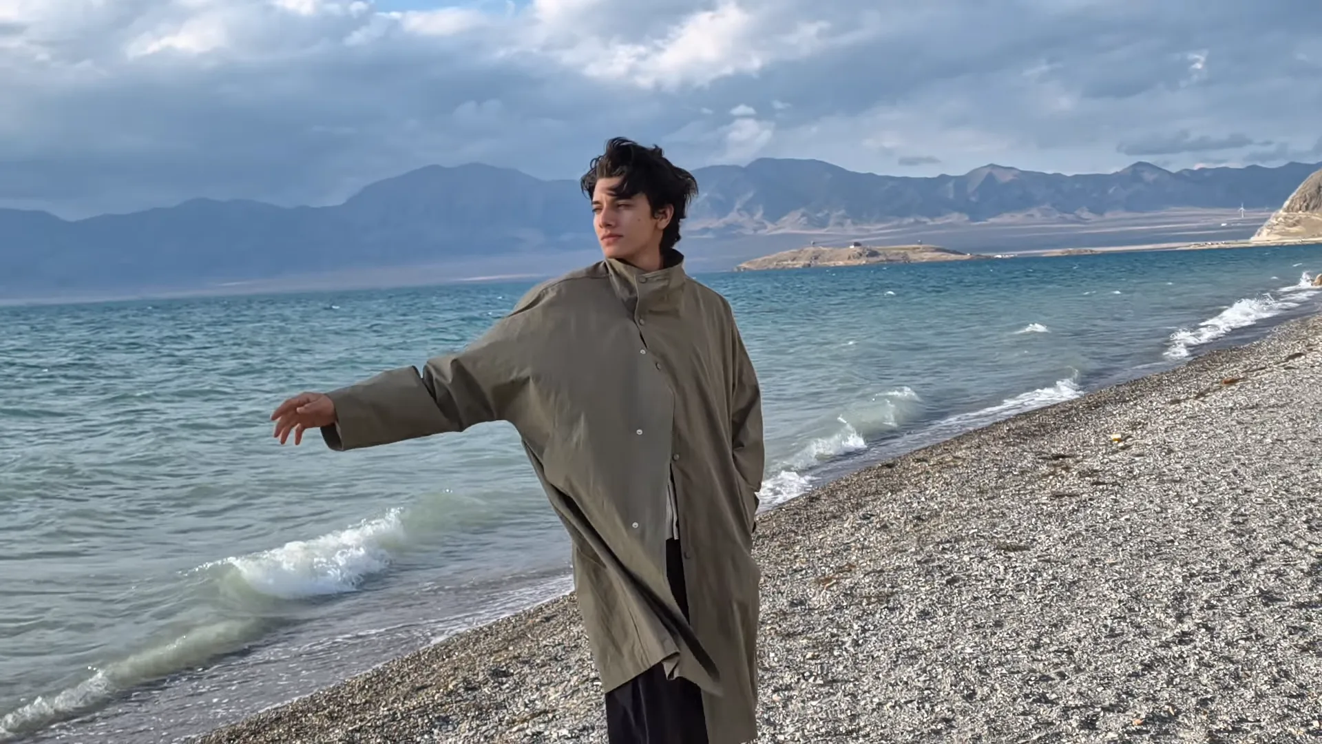 Film ukazujący mężczyznę na plaży oraz krajobraz w tle