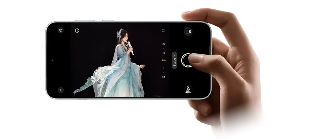 Dłoń trzymająca poziomo smartfon z widokiem aparatu i piosenkarką w błękitnej sukni na ekranie