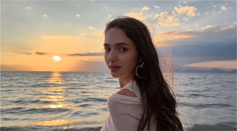 Młoda dziewczyna na plaży na tle zachodzącego słońca